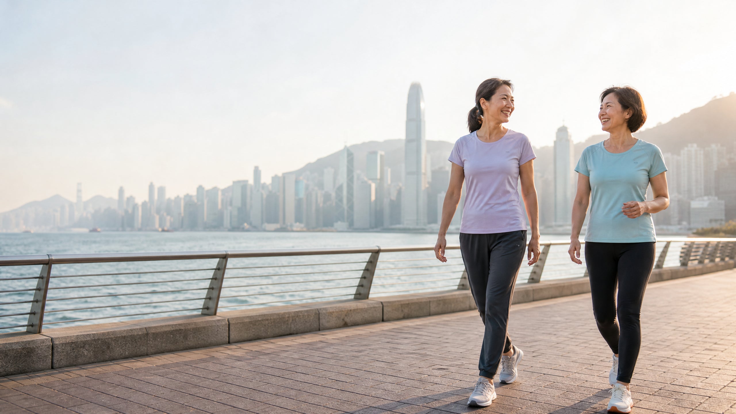 Two Asian women walking at Hong Kong waterfront in daylight — everyday bone health lifestyle